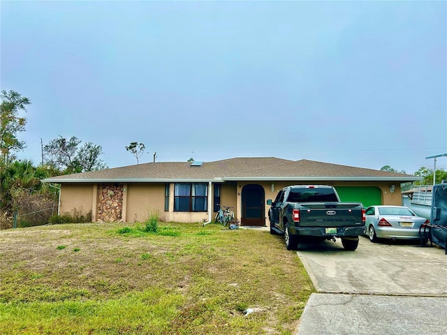 ranch-style home featuring stucco siding, an attached garage, a front yard, stone siding, and driveway