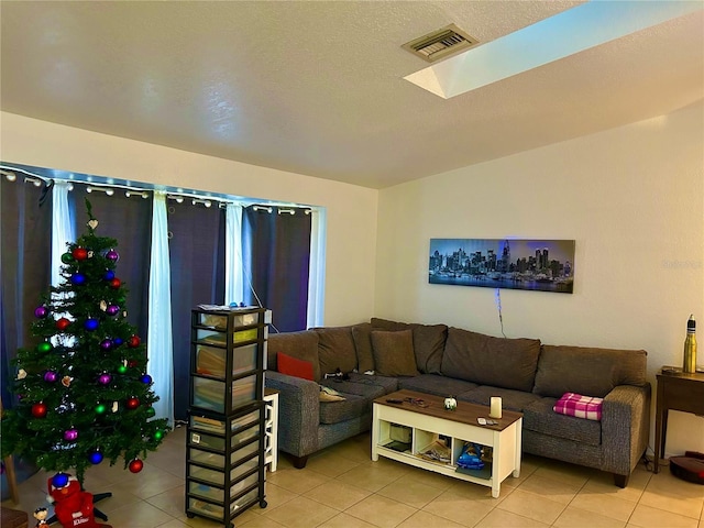 living area featuring vaulted ceiling with skylight, visible vents, and light tile patterned flooring