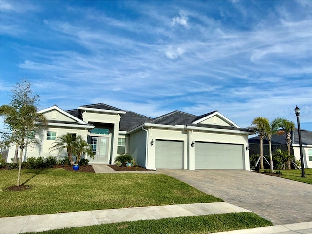 view of front facade with decorative driveway, an attached garage, a front lawn, and stucco siding