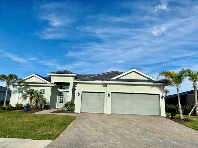 single story home featuring an attached garage, a front lawn, decorative driveway, and stucco siding