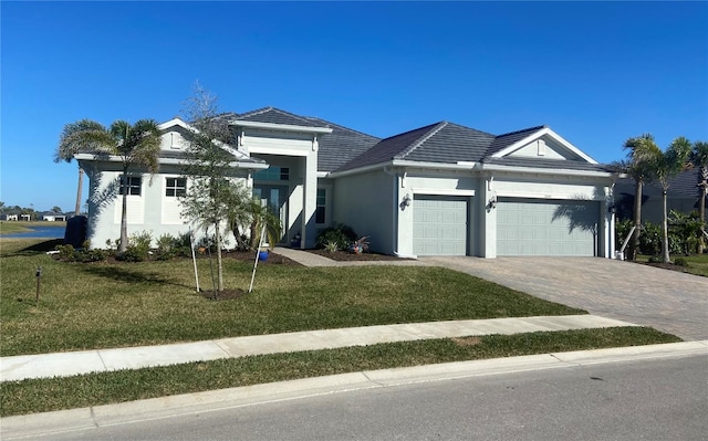 single story home featuring decorative driveway, stucco siding, an attached garage, a tiled roof, and a front lawn