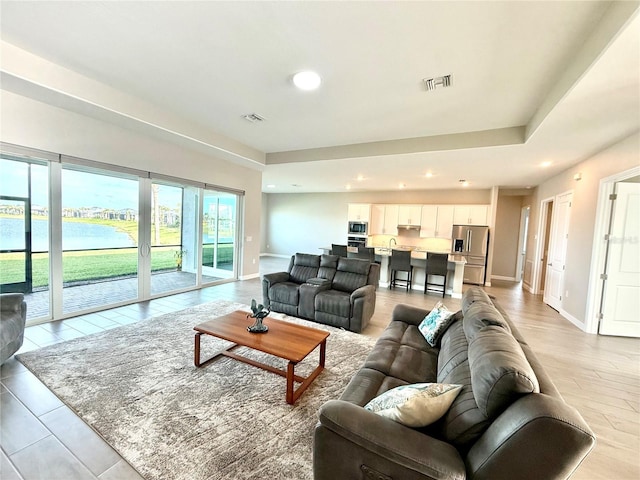 living area with recessed lighting, visible vents, a water view, and baseboards