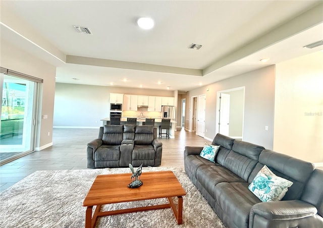 living room with light wood-style floors, recessed lighting, visible vents, and baseboards