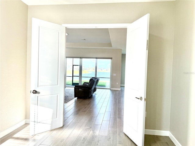 hallway featuring light wood-type flooring and baseboards