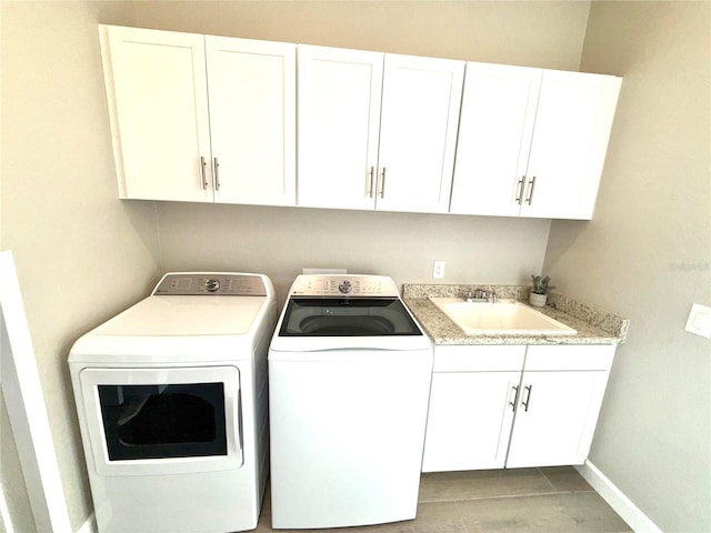 laundry room featuring cabinet space, baseboards, washer and clothes dryer, and a sink