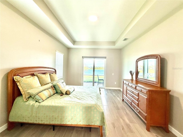 bedroom with a raised ceiling, visible vents, light wood-style floors, access to outside, and baseboards