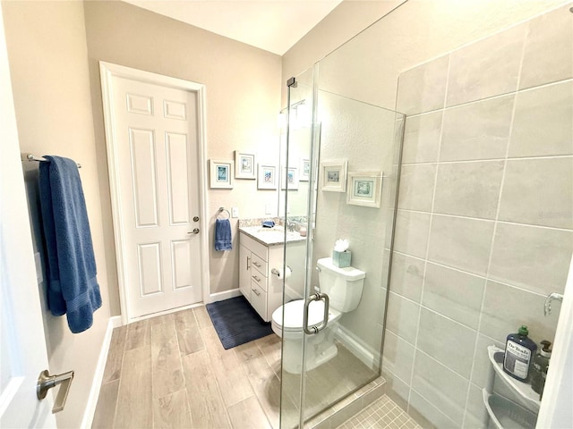 full bath featuring baseboards, toilet, wood finished floors, vanity, and a shower stall