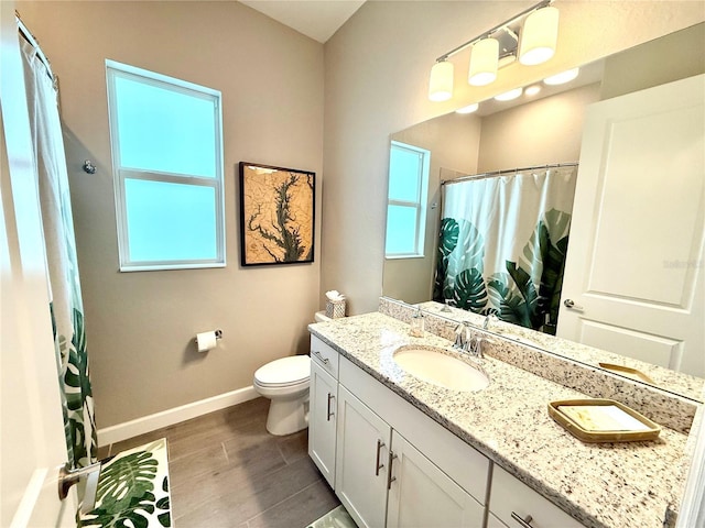 full bath featuring a healthy amount of sunlight, wood finished floors, vanity, and baseboards