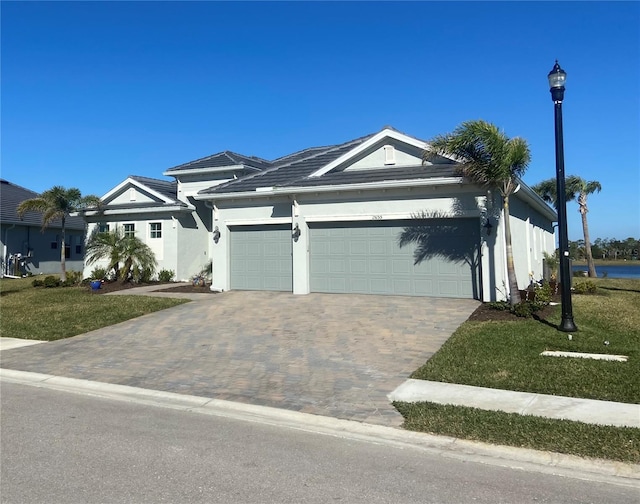 ranch-style home featuring a garage, a front lawn, decorative driveway, and stucco siding