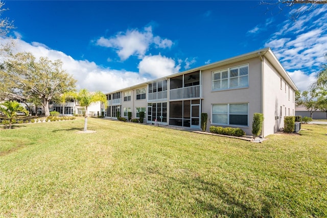 back of property featuring a lawn and stucco siding