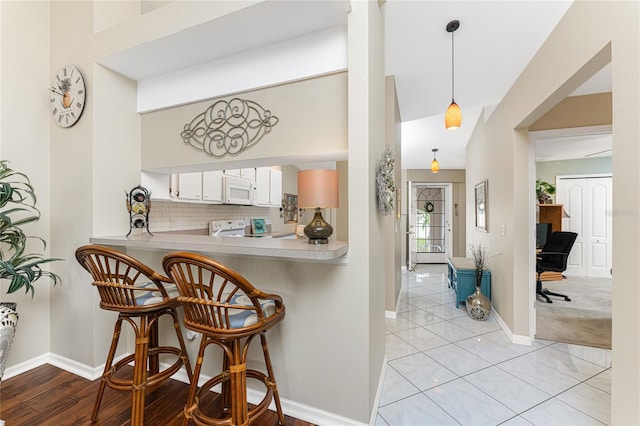 bar featuring white microwave, baseboards, range, and backsplash