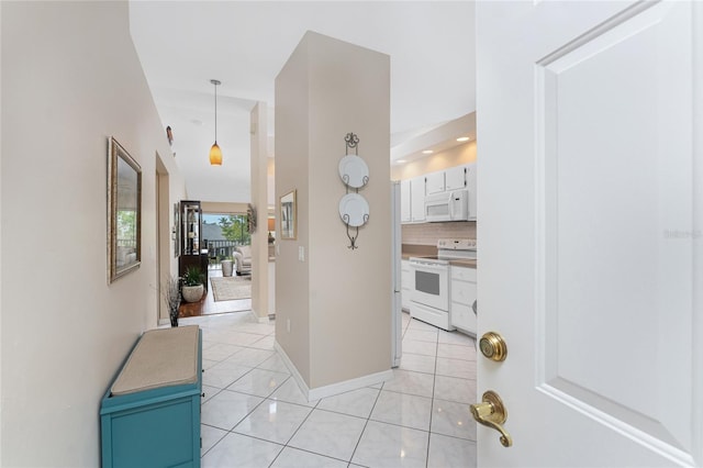 hall featuring light tile patterned floors and baseboards