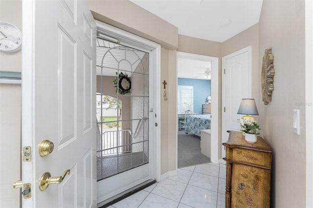 doorway featuring light tile patterned floors and a ceiling fan