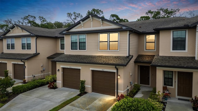 multi unit property with stucco siding, driveway, and a shingled roof