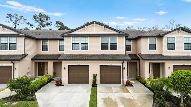 multi unit property featuring stucco siding, a garage, driveway, and a shingled roof