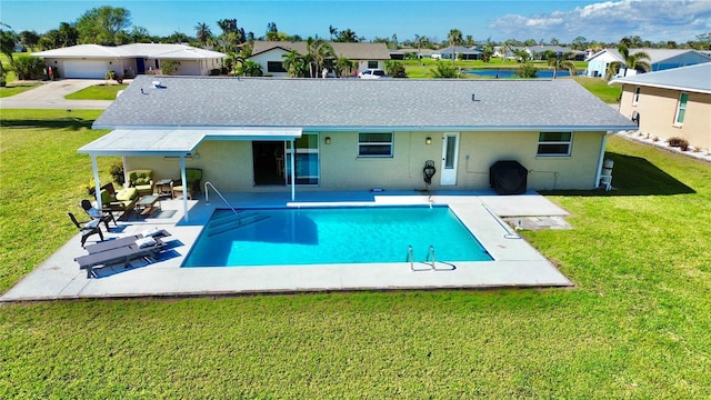 rear view of property featuring a patio area, a residential view, an outdoor pool, and a yard