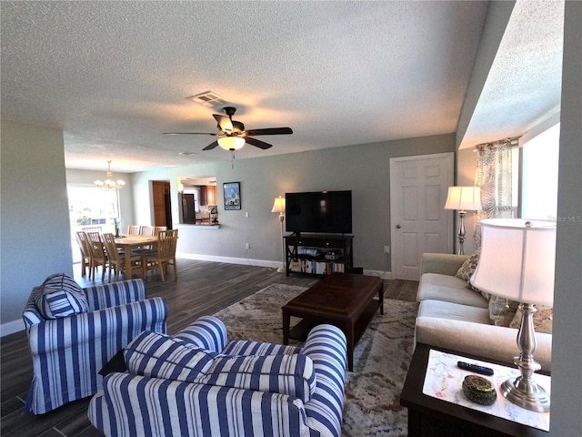 living area with visible vents, a textured ceiling, baseboards, and wood finished floors