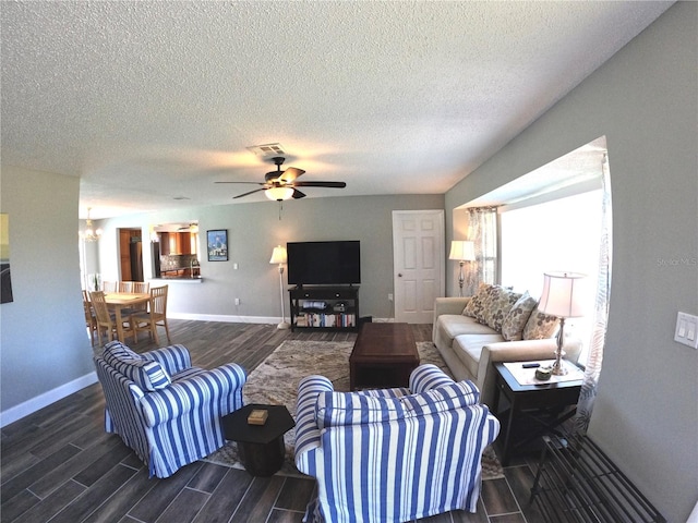 living area featuring ceiling fan with notable chandelier, baseboards, visible vents, and wood tiled floor