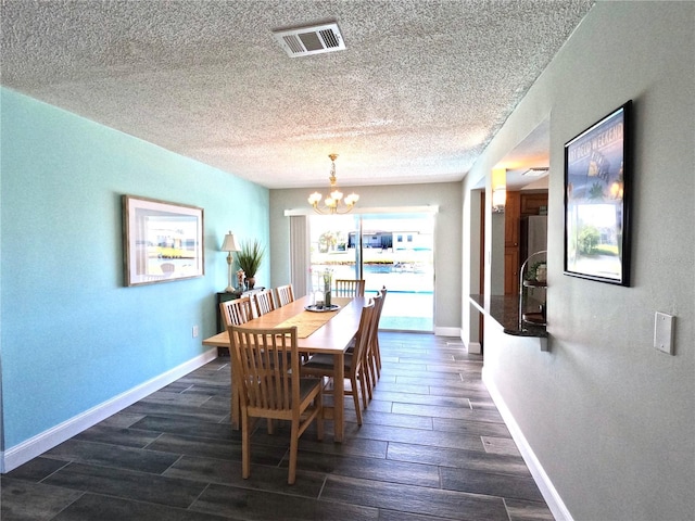 dining space with baseboards, a textured ceiling, visible vents, and wood tiled floor