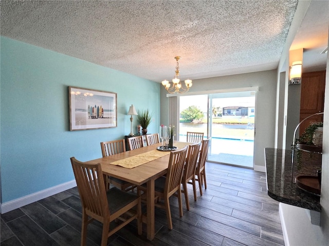 dining space featuring wood tiled floor, a textured ceiling, baseboards, and a notable chandelier