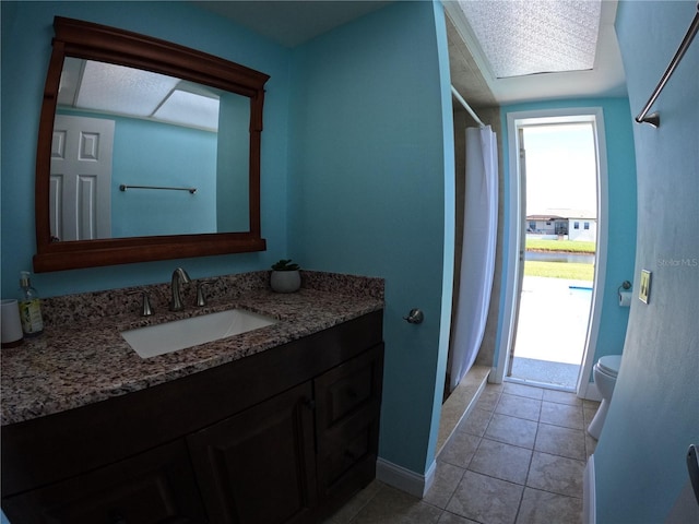 bathroom with toilet, vanity, a shower with curtain, baseboards, and tile patterned floors