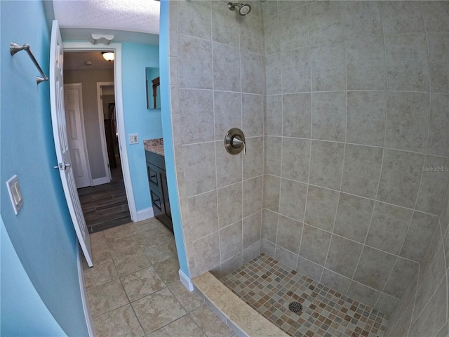 full bath featuring a textured ceiling, a shower stall, vanity, and tile patterned floors