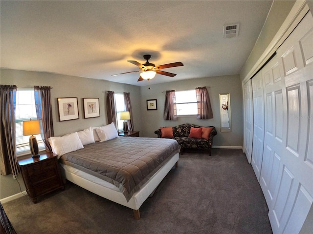 bedroom featuring visible vents, multiple windows, dark carpet, and baseboards