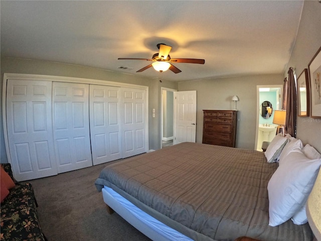 carpeted bedroom featuring a ceiling fan, ensuite bath, visible vents, and a closet