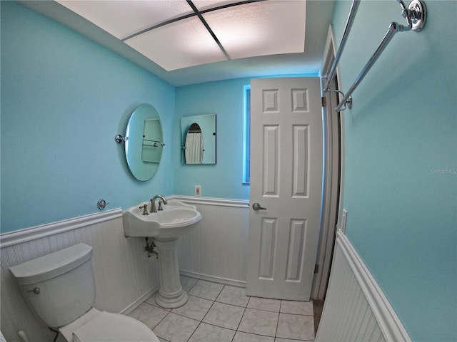 bathroom featuring tile patterned flooring, a wainscoted wall, and toilet