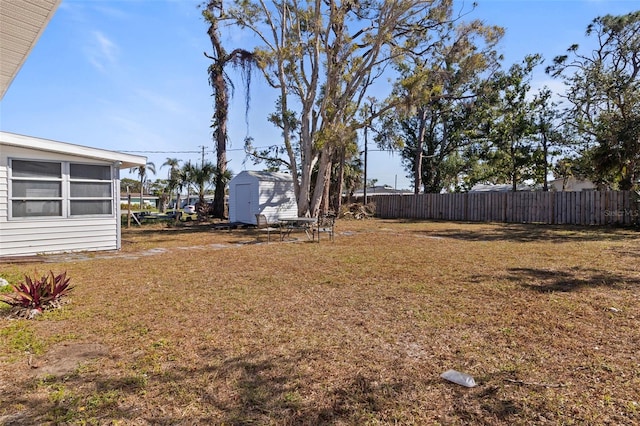 view of yard featuring an outbuilding, a storage unit, and fence