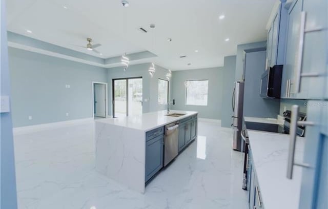 kitchen featuring marble finish floor, a raised ceiling, appliances with stainless steel finishes, open floor plan, and an island with sink