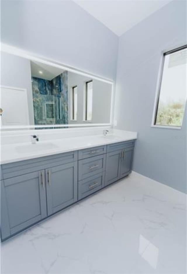 bathroom featuring marble finish floor, a sink, and double vanity