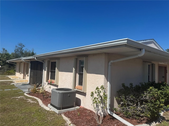 view of side of property with cooling unit and stucco siding