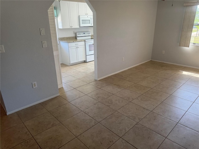 spare room with light tile patterned flooring and baseboards