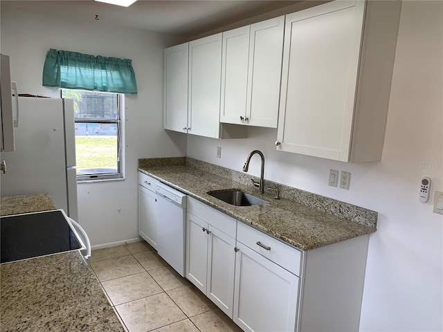 kitchen with white appliances, light tile patterned floors, white cabinets, light stone counters, and a sink