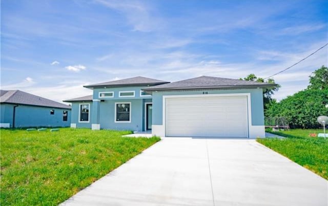 prairie-style home with an attached garage, driveway, a front lawn, and stucco siding