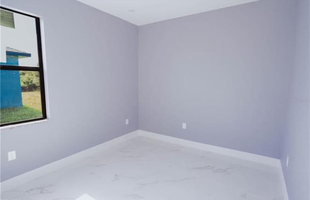 unfurnished room featuring marble finish floor and baseboards