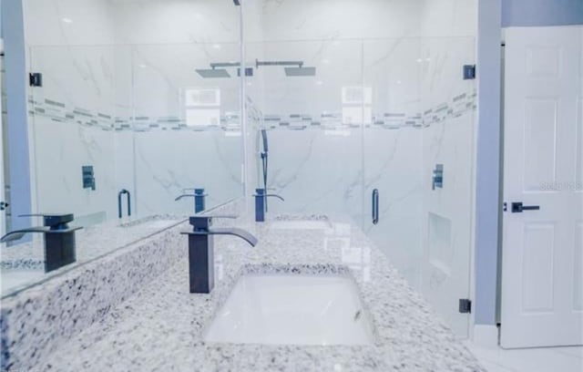 bathroom featuring double vanity, a sink, and a marble finish shower