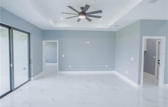 spare room featuring ceiling fan, recessed lighting, baseboards, marble finish floor, and a raised ceiling