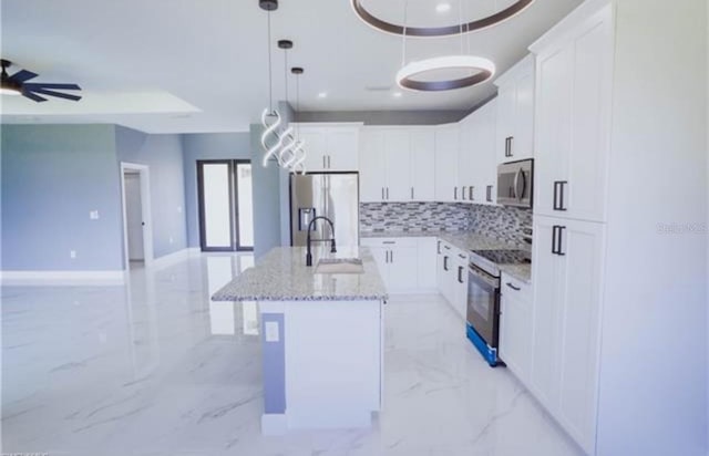 kitchen featuring white cabinets, marble finish floor, a center island with sink, and stainless steel appliances