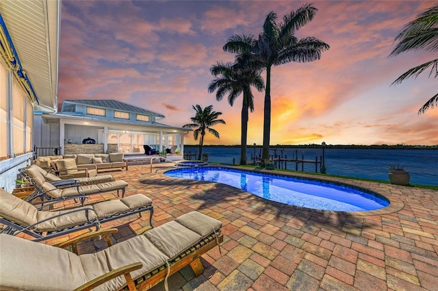 pool at dusk featuring an outdoor living space, an outdoor pool, a hot tub, and a patio