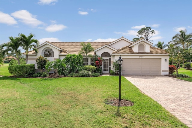 view of front facade with decorative driveway, a tile roof, stucco siding, a garage, and a front lawn