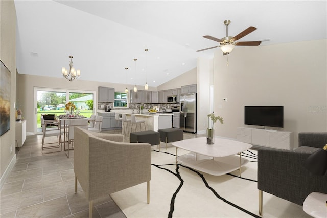 living room featuring high vaulted ceiling, baseboards, and ceiling fan with notable chandelier