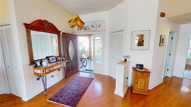 entryway featuring visible vents, a high ceiling, baseboards, and wood finished floors