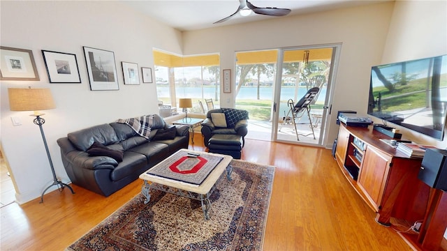 living room with light wood finished floors, a ceiling fan, and baseboards