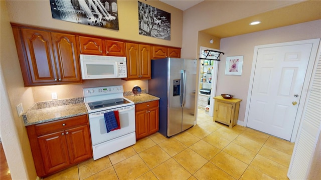 kitchen featuring white appliances, light tile patterned floors, brown cabinetry, light stone countertops, and recessed lighting