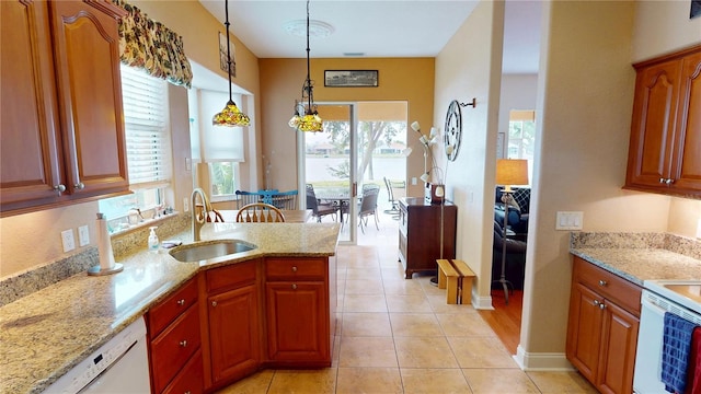 kitchen featuring decorative light fixtures, a sink, dishwasher, and light stone countertops