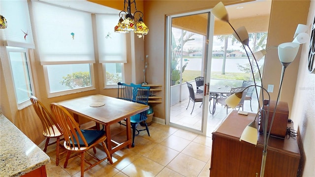 dining space featuring a water view, light tile patterned floors, and baseboards