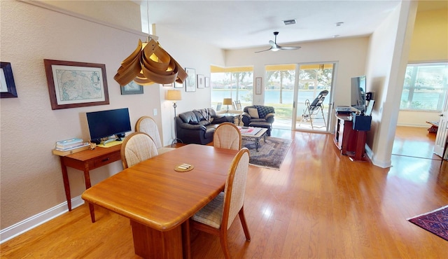 dining area with light wood-type flooring, a healthy amount of sunlight, visible vents, and baseboards