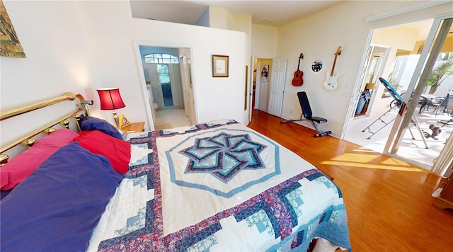 bedroom with connected bathroom, multiple windows, and wood finished floors